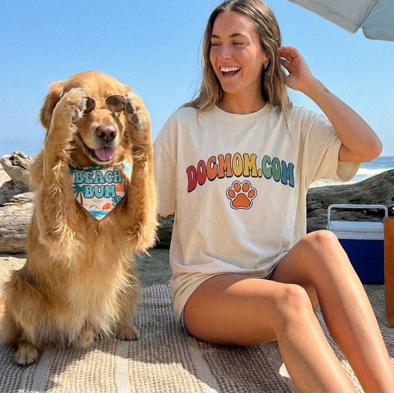Woman and dog sitting on a beach with 'Dogmom' branded items.