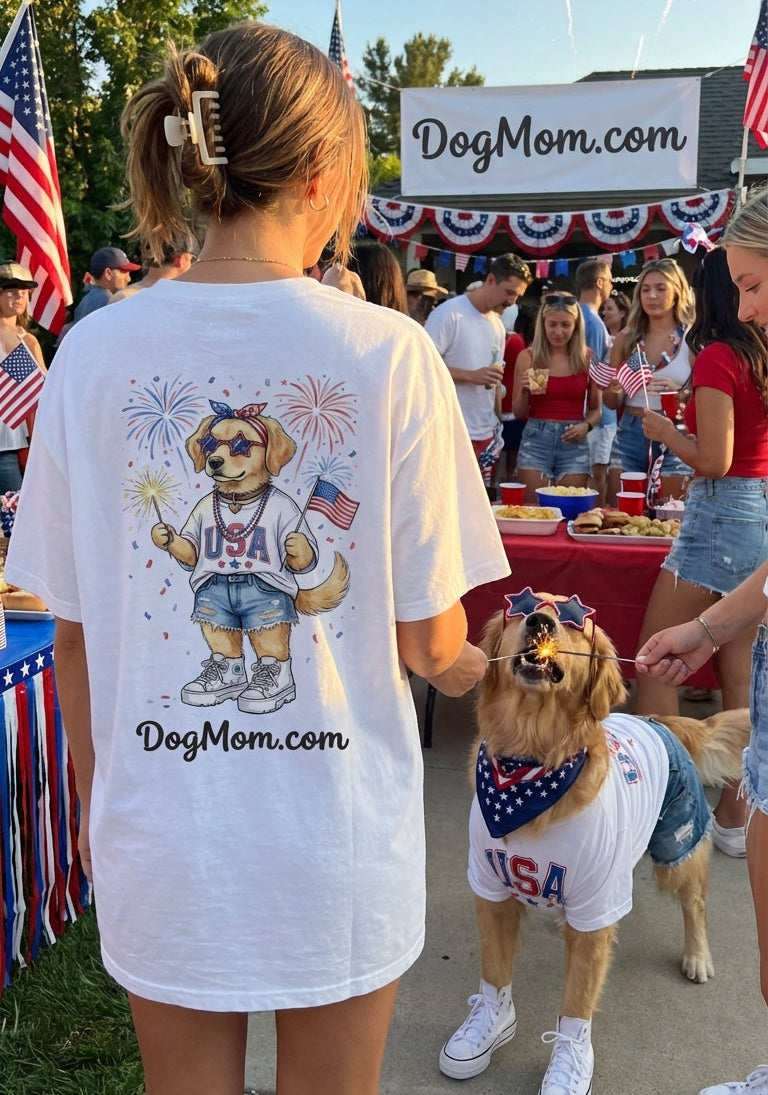 Woman wearing a 'DogMom.com' t-shirt with a dog, both in front of a 'DogMom.com' booth with fireworks in the background.