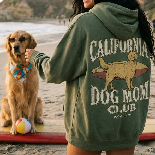 Woman in a hoodie with a dog on a surfboard at the beach